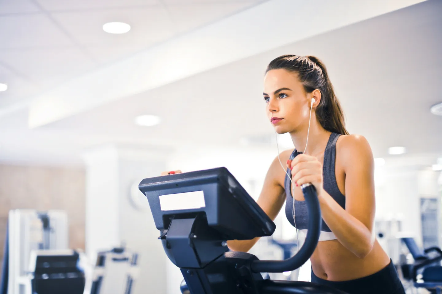 A woman exercising on a cardio machine in a bright gym